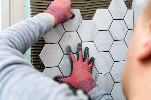 azulejos - hombre poniendo baldosas hexagonales textura de mármol en la pared photo