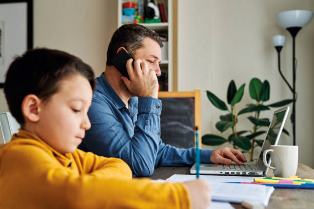 istock Businessman working at home with child. Child is making homework. 1217184230