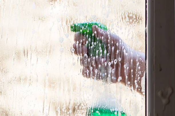 istock Man cleaning window using window cleaning squeegee and cleaning sprayer, cleaning services concept. Housework and housekeeping concept 1217184293