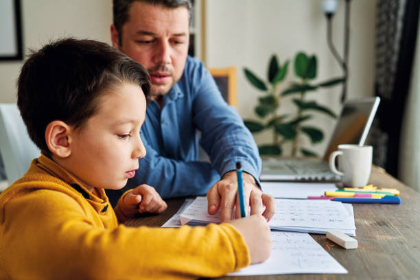 istock Businessman working at home with child. Child is making homework. 1217185113