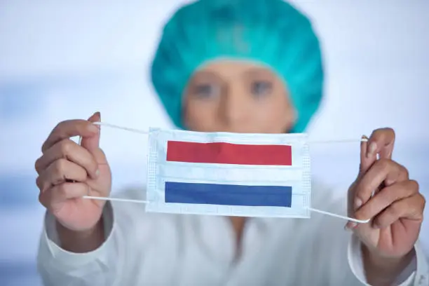 Female doctor with surgical cap presenting mouthguard with flag of Netherland