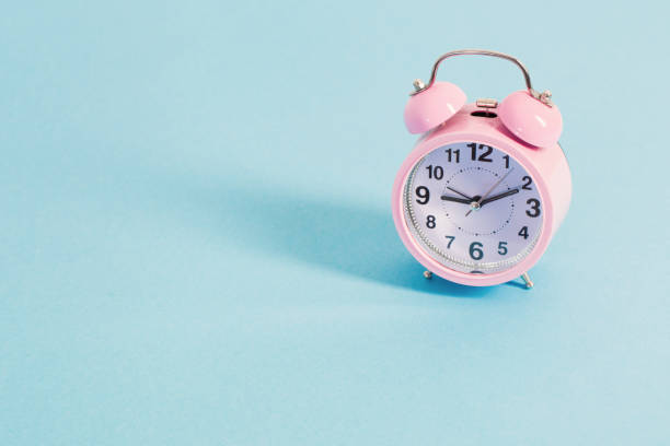istock pink alarm clock on blue background 1217186377