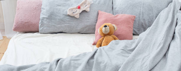 istock bed with teddy bear on gray linens 1217186381
