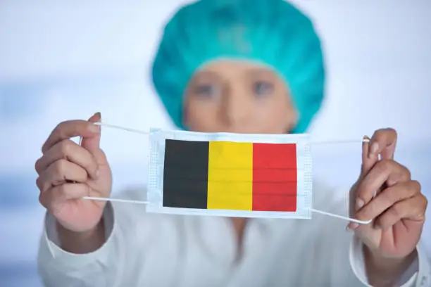 Female doctor with surgical cap presenting mouthguard with flag of Belgium