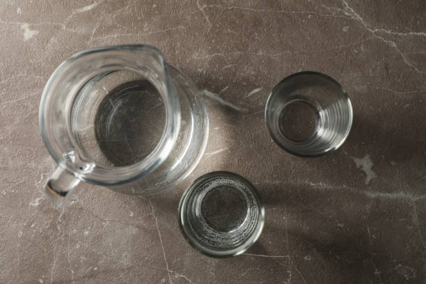 istock Jug with water and glasses on gray table, top view 1217191643