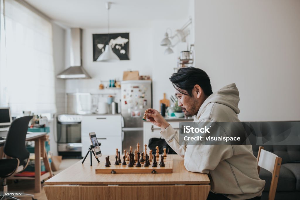 Japanse mens die virtueel schaak met vriend online tijdens sociale het distantiëren tijden speelt - Royalty-free Huiselijk leven Stockfoto