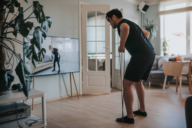 японский человек принимая онлайн фитнес-уроки во время блокировки в изоляции - living room learning healthy lifestyle one person стоковые фото и изображения