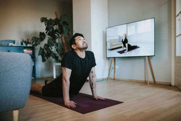 Japanese man taking online yoga lessons during lockdown in isolation Photo series of stay-at-home fitness during lockdown in self isolation. illness prevention photos stock pictures, royalty-free photos & images
