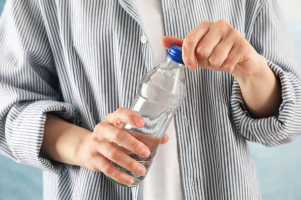 istock Person in shirt opens a bottle, close up 1217192114