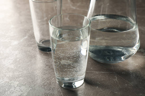 istock Jug with water and glasses on gray table, close up 1217192554