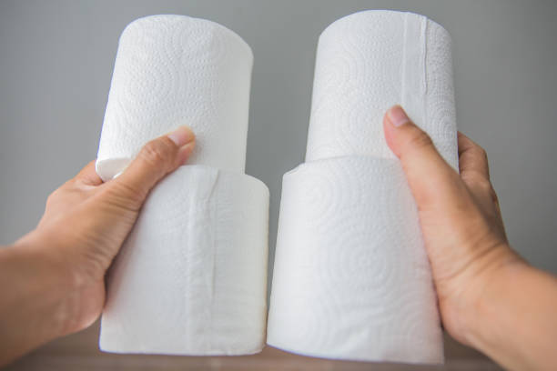 Close up Indonesian woman buying large group of toilet paper rolls, and holding it with both of her hands, at supermarket.