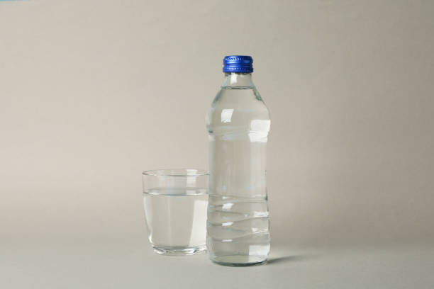 istock Bottle and glass with water on gray background, space for text 1217192902