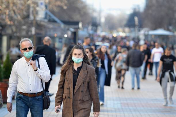 Man and woman walking in the the city center wearing protective masks Sofia, Bulgaria - MAR 13 2020: A young woman and an older man are walking on Vitosha street. Few hours after that the Governemnt announced State of Emergency in the country because of the corona virus outbreak. bulgaria stock pictures, royalty-free photos & images