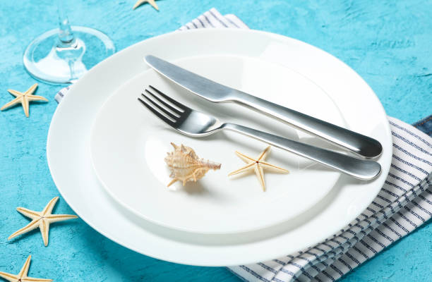 istock Table setting with seashells and starfishes on turquoise background, close up 1217194608
