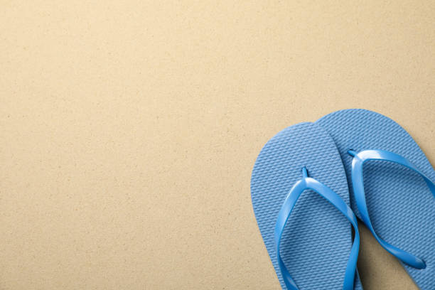 istock Flip flops on sea sand background, space for text 1217195265