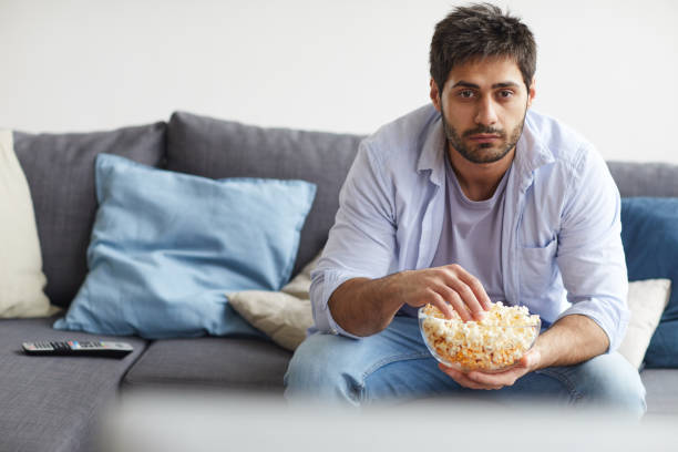 homme adulte observant la tv à la maison - television boredom men sofa photos et images de collection