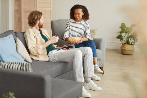 istock Modern Couple Eating Popcorn while Watching TV at Home 1217195501