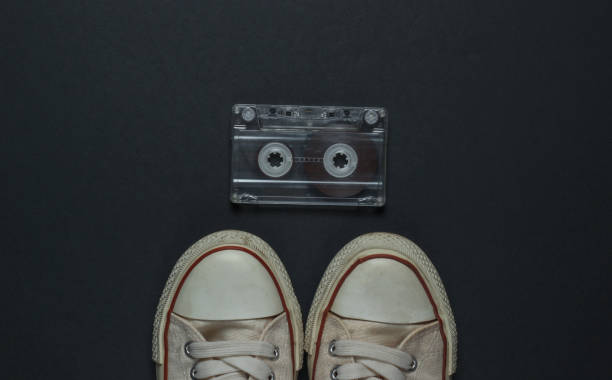 istock Retro old sneakers and audio cassette on a black background. 80s. Top view 1217195696