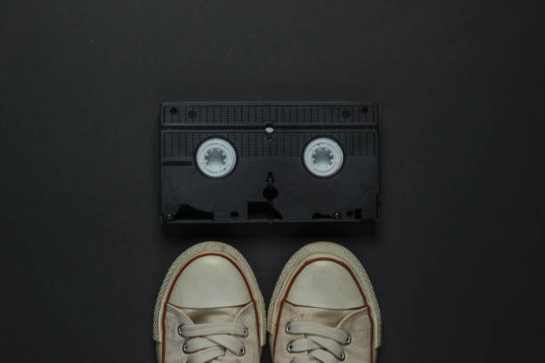 istock Retro old sneakers and video cassette on black background. 80s. Top view 1217195773