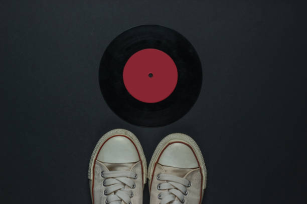 istock Retro old sneakers and vinyl record on a black background. 80s. Top view 1217195839