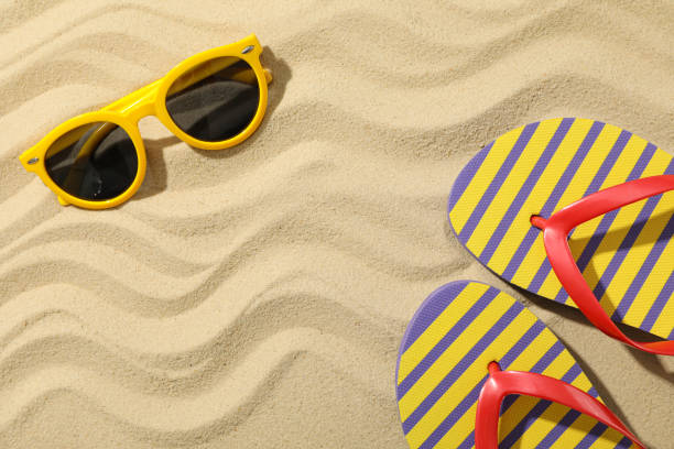istock Flip flops and sunglasses on sea sand, space for text 1217196147