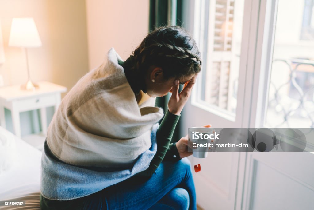 Staying home with flu virus Woman with temperature staying home wrapped in scarf and drinking hot tea Illness Stock Photo