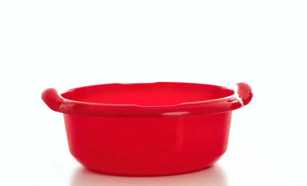 Cleaning wash bowl, plastic hand basin red color isolated against white background, Domestic household cleaning