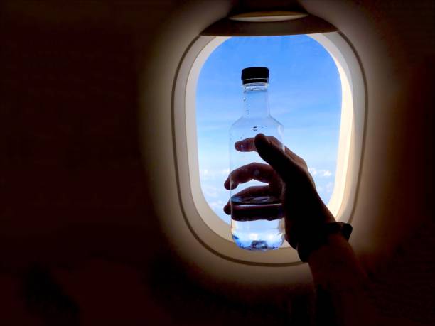 istock hand holding water bottle near airplane window 1217201017