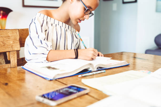 istock Junior high age girl sits at home in the dining room doing schoolwork 1217201117