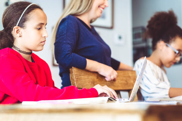 istock Mother supervises her school age daughters at home doing distance learning or schoolwork 1217201496