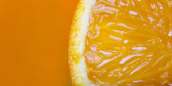 Slice of fresh orange fruit isolated on orange background.