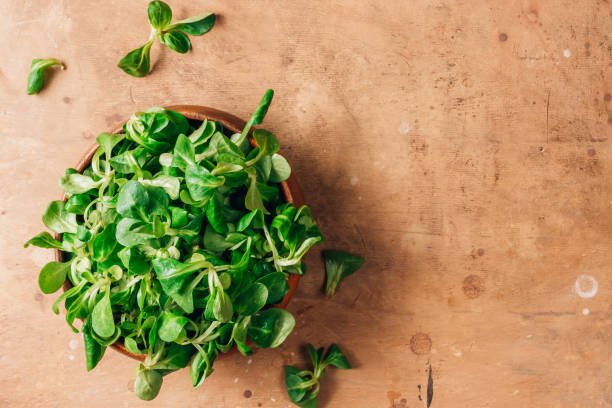 istock Wooden bowl with corn salad leaves on rustic background. Top view. 1217204783