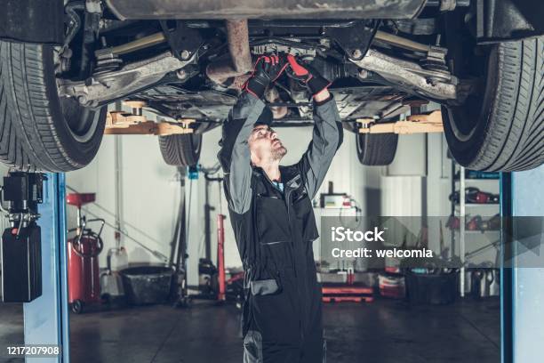 Mechanic Fixing Car On A Lift Stock Photo - Download Image Now - Car, Auto Mechanic, Repairing