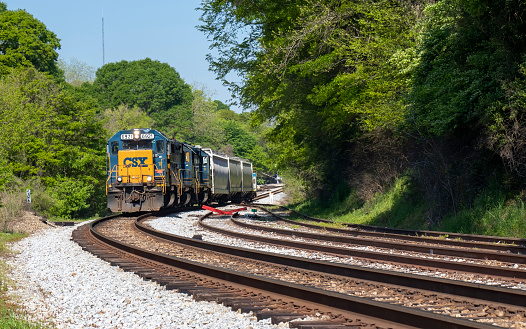 Athens, Georgia - April 6, 2020: CSX engine 6921 pulls a small load through a crossing around a curve in the track.
