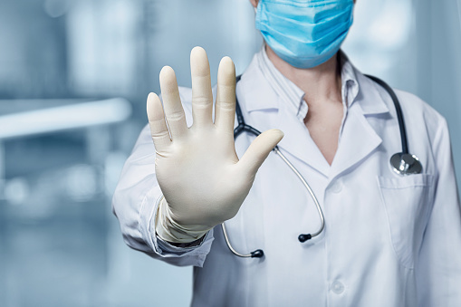 Doctor shows with his hand a ban on a blurred background.