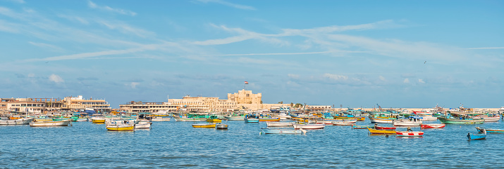Panorama of the city of Alexandria, Egypt.  Fishing boats in the Bay and Citadel of Qaitbay fortress at the background.