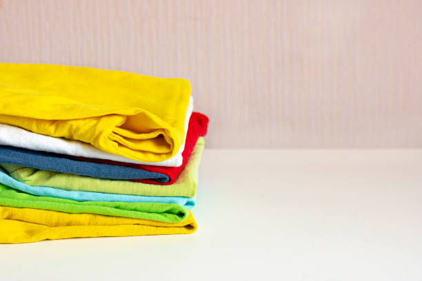 istock A stack of children's cotton multi-colored clothes on a white table. Clean things. Household concept. 1217215578