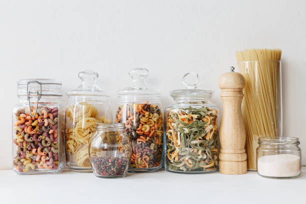 Various cereals and seeds in glass jars on the white textured background. Kitchen interior ideas. Eco friendly kitchen, zero waste home concept