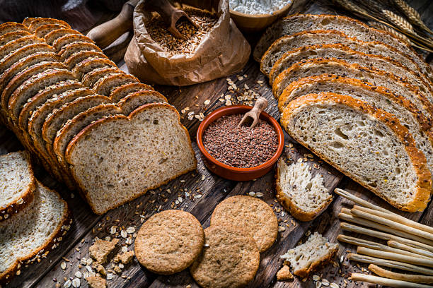 nourriture saine : pain de grains entiers avec des graines et des céréales sur la table rustique de cuisine - mixed bread photos et images de collection