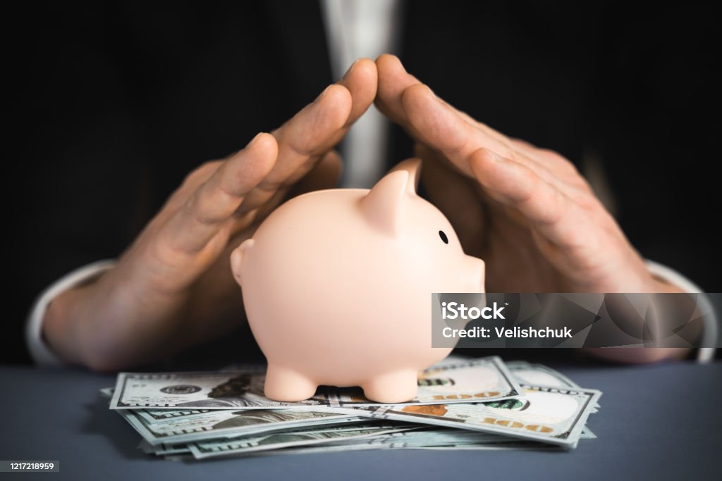 Money Protecting concept. Saving symbol - Close-up Of A Human Hand Protecting Pink Piggy Bank Protection Stock Photo