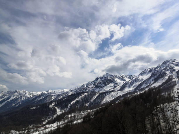 istock Snow-capped mountain peaks against the blue sky with white clouds 1217219516
