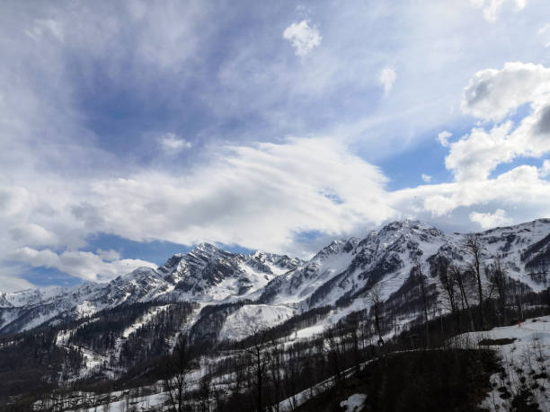 istock Snow-capped mountain peaks against the blue sky with white clouds 1217219568