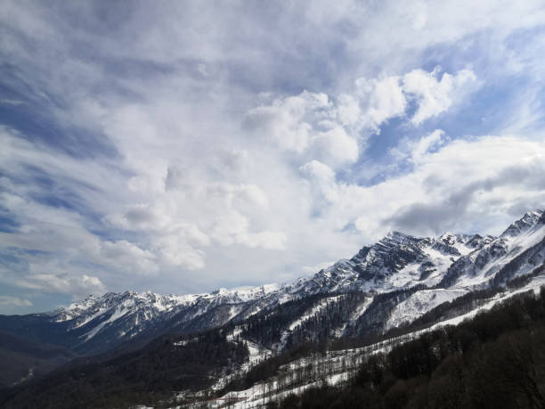 istock Snow-capped mountain peaks against the blue sky with white clouds 1217219601