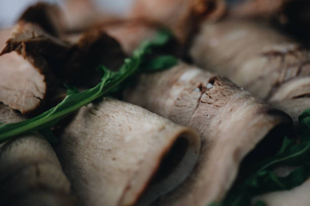 Thin slices of meat, ham, bacon lie on a white plate. The meat is planted on toothpicks, samples of products for testing