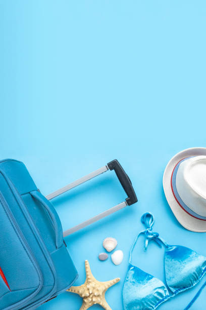 istock Set travel accessories on blue background. Beach hat, suitcase, starfish, shells for woman's summer holidays. Vertical fashion concept, top view, flat lay 1217222928