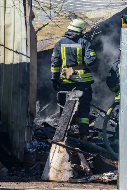 A strong and brave fireman rescues a burning building using water in a fire operation. Fireman in a fire protection suit. The elimination of a real fire.