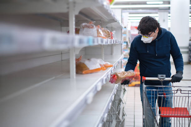 manos de hombre en guantes de protección buscando pan en estantes vacíos en una tienda de comestibles - vacío fotografías e imágenes de stock