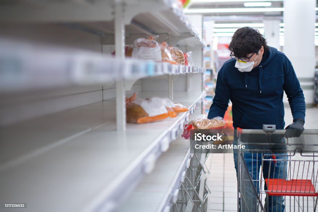Man's hands in protective gloves searching bread on empty shelves in a groceries store Man's hands wearing rubber gloves holding product in a supermarket during an epidemic of an infectious disease Empty Stock Photo