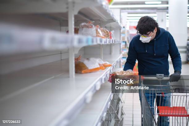 Mans Hands In Protective Gloves Searching Bread On Empty Shelves In A Groceries Store Stock Photo - Download Image Now