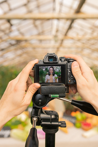 Close-up of unrecognizable camera operator preparing for shooting video review on farm products